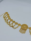 Angled close-up of the waist belt showing engraved filigree coin discs, diamond-shaped charm drops on swag chains, and the large central medallion with multi-strand chain tassel