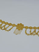 Angled close-up of the waist belt showing open-lattice filigree rosette medallions, diamond-shaped charm drops on swag chains, and the large leaf-petal floral centerpiece with chain tassel