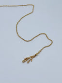 Angled view of the lariat waist chain showing the graduated faceted bead chain and one multi-strand tassel drop with twisted rope knot