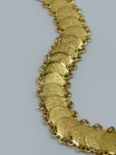 Close-up of the waist belt showing repeating round coin discs engraved with dense scrollwork and calligraphic-style motifs, linked by jump rings