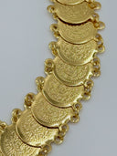 Macro close-up of the engraved coin discs showing the dense scrollwork and calligraphic-style motif detail and jump ring connections on both edges