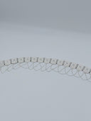 Full arc flat lay view of the silver-tone diamond-cut octagonal panel waist belt showing the full row of hinged panels and swag cable chains along the lower edge