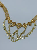 Close-up of the front V-drape showing multiple heart-shaped fan medallions with radial sunburst engraving, white bead centers, and cascading multi-strand coin disc drop chains