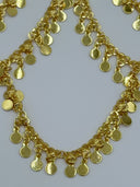 Extreme macro close-up of the flat round coin disc drop chains showing the individual disc links, jump ring connections, and warm gold-tone finish of the swag fringe