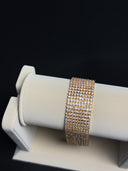 Gold bracelet on a white jewelry display with a black background