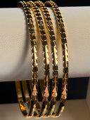 Stack of gold bracelets on a white cylindrical stand