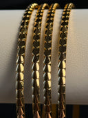 Gold bracelets with textured design on a white cylindrical object
