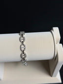 Silver bracelet with diamonds on a white stand against a black background