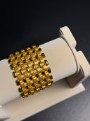 Gold bracelet on a white stand against a dark background