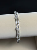 Two pearl and crystal bracelets on a white cylindrical stand with a black background