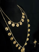 Close-up of a gold-tone layered necklace set showing two chains adorned with textured flower charms of varying sizes against a dark background