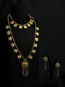 Full view of a gold-tone two-necklace and earring set on a black bust, featuring flower charms along both chains and a tassel pendant on the longer necklace