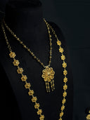 Close-up of gold-tone filigree flower-link chain necklaces on black bust, showing repeating petal motifs and openwork flower pendant with dark bead tassel fringe