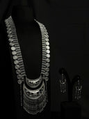 Silver-tone 2-piece tribal-boho jewelry set on black bust — long coin chain necklace with layered crescent pendant and chain tassel fringe, with matching drop earrings