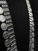 Close-up of silver-tone multi-row chain band with engraved Arabic calligraphy-style coin medallions, showing oxidised antique finish and texture detail