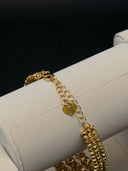 Gold-tone open-band ring with floral bead detailing and barrel push clasp, placed on white jewellery display