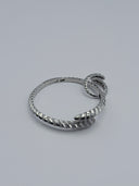 Close-up of double-coil serpent head terminal on silver-tone pavé scale bangle showing crystal detailing and high-polish finish