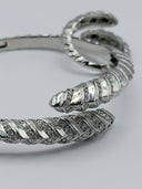 Macro detail of alternating high-polish and pavé crystal scale segments on silver-tone Serpenti-style hinged bangle
