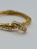 Close-up of gold-tone Tubogas-inspired bangle showing stacked granulated disc rings and tapered bullet terminal detail