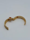 Side view of the Andalus hinged bangle open, showing the hinged clasp mechanism, beaded border edges, and red stone accents along the filigree body
