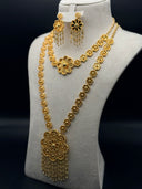 Gold-tone Zahra floral jewelry set on a white bust display, featuring a long flower link necklace with cluster pendant, tassel fringe, and matching chandelier earrings