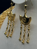 Close-up of the Hilal crescent hook earrings showing the beaded inner border, circular centre detail, and three chain tassels tipped with gold-tone ball drops
