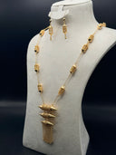 Gold-tone Fanous jewelry set on a cream bust, showing a long cable chain necklace with alternating filigree lantern and oval beads, cascading three-lantern pendant, and matching hook earrings