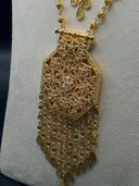 Detail of the Rawdha hexagonal open-lace pendant showing dense arabesque scrollwork and wide multi-strand fringe of engraved disc-link chains tipped with teardrop drops