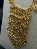 Detail of the Majd crescent filigree pendant showing dense arabesque scrollwork and wide cascading multi-strand fringe of engraved bead and leaf drop chains