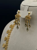 Close-up of the matching drop earrings showing an eye-shaped filigree top with teardrop and oval link fringe drops in gold tone