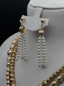 Close-up of the drop earrings showing a ribbed gold-tone bead cap over multi-strand white pearl-finish round bead tassels