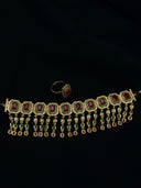Gold-tone choker with octagonal ruby-red stone links, cascading tassel drops with mixed-cut coloured stones, and matching halo ring, photographed on a black background