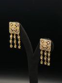 Pair of gold-tone drop earrings with a square pavé panel top and three tassel chains of individually set cushion-cut clear stones, displayed on a black velvet stand