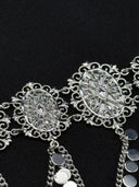 Close-up of two oval filigree medallion links on the choker showing the scalloped lace border and intricate openwork botanical pattern, with disc-drop chains below