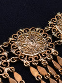 Macro detail of a single octagonal filigree medallion from the choker, highlighting the raised sunburst and botanical openwork pattern inside the gold-tone scrollwork frame