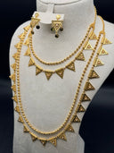 Close-up of gold-tone triangular pendants with textured coin-scale surface and pearl-like bead center accents on a beaded ball chain