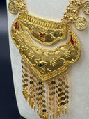 Detail close-up of the bib pendant tiers — star motifs with red and dark stone accents, floral embossing, and coin disc tassel fringe in gold tone