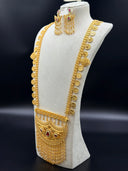 Close-up of the horizontal bar connector on the Khaleeji filigree crescent bib necklace showing floral cutouts with turquoise-color bead centers and torpedo drop fringe