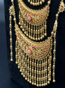 Close-up of a long gold-tone side chain featuring three rows of star-burst filigree medallion links with pink and white stone accents, connected by granulated ball links