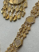 Close-up of the pendant charm fringe and the geometric plaque-link necklace chain, showing mixed kite, coffin, and diamond-shaped charms in stone-set and ridged gold-tone finishes