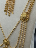 Detail shot of the necklace showing a filigree medallion station with bead tassel drops and coin disc ends alongside the textured ball-link chain strands