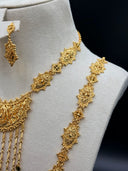 Detail shot of the engraved diamond-shaped plaque chain stations and the open filigree crescent pendant with raised teardrop centerpiece and scrolling vine motifs, with chain tassel fringe visible below
