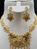 Close-up of the matching drop earrings and the shorter crescent pendant necklace on a white bust, showing the engraved diamond-shaped earring bodies with raised teardrop centers and single tassel drops