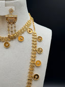 Close-up of the coin chain necklace showing engraved round coin discs with star and crescent motifs and beaded border edges, alongside the half-moon filigree pendant with pave stone floral clusters and chain tassel fringe