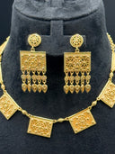 Close-up of the matching drop earrings showing a round engraved disc stud top, a square open-filigree plaque body with raised floral detailing, and a row of floral bead drops with engraved teardrop finishes, displayed against the shorter collarbone necklace
