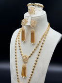 Front view of the full set on a white bust showing both bead chain necklaces layered together with lotus pendants and chain tassels, the chandelier earrings, bracelet, and lotus cocktail ring displayed at the top