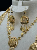 Close-up of the matching drop earrings showing the round open filigree sunburst body with crosshatch-engraved center and three engraved teardrop charm drops, alongside the upper necklace medallion