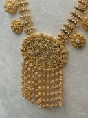 Close-up of the upper necklace section showing the diamond-link clover chain structure with coin disc drops and the transition into the oval filigree pendant with its scalloped border and stone-set floral body
