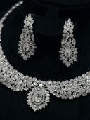 Close-up of the collar necklace and chandelier earrings showing dense marquise and round-cut clear stone paving in a floral leaf arrangement