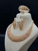 Three-quarter angle view of the full set on a white bust highlighting the wide collar necklace, leaf cluster chandelier earrings, cuff bangle, and ring